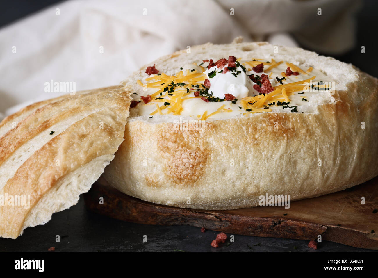 Heiße Kartoffel Suppe in einer sauerteigbrot Schüssel mit saurer Sahne, Cheddar Käse, getrockneter Schnittlauch und Bacon bits. Extrem flache Tiefenschärfe mit selektiven Stockfoto