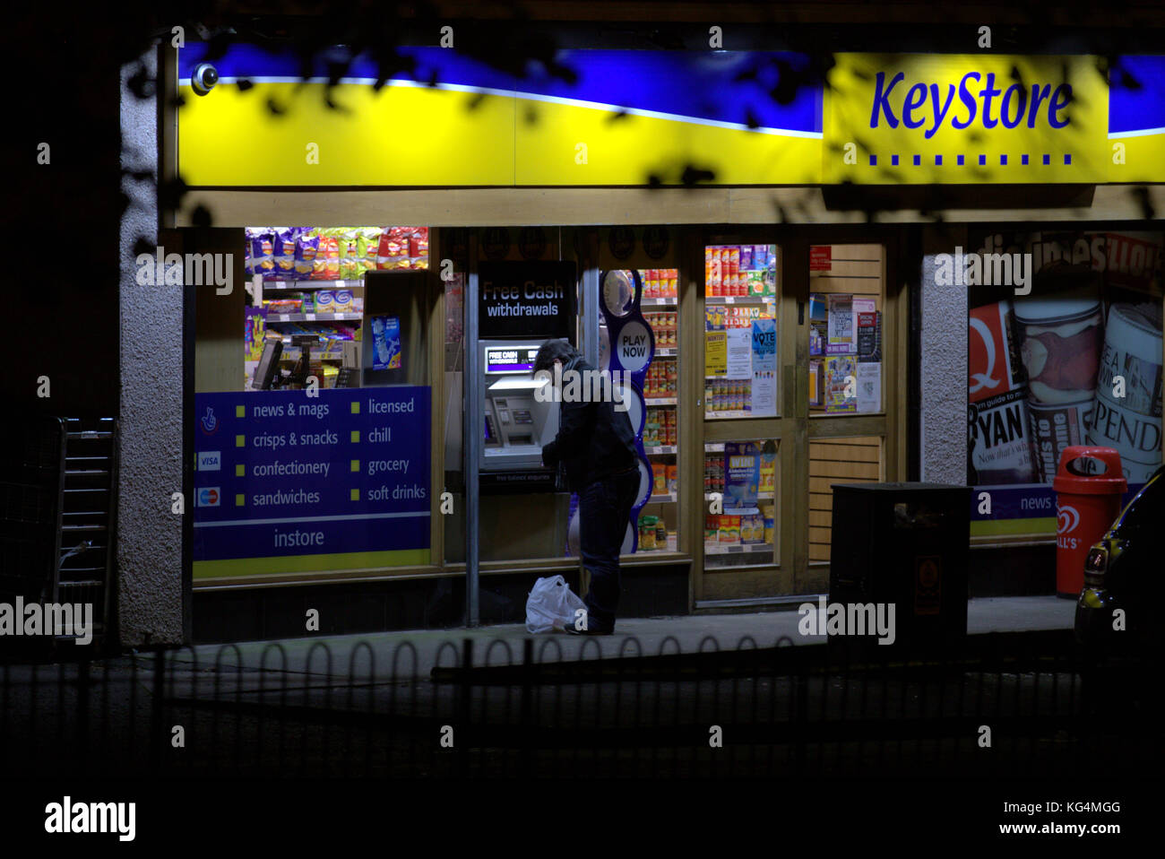 Mann mit paypoint Geldautomat im Convenience Store in der Nacht gesehen von hinten Stockfoto