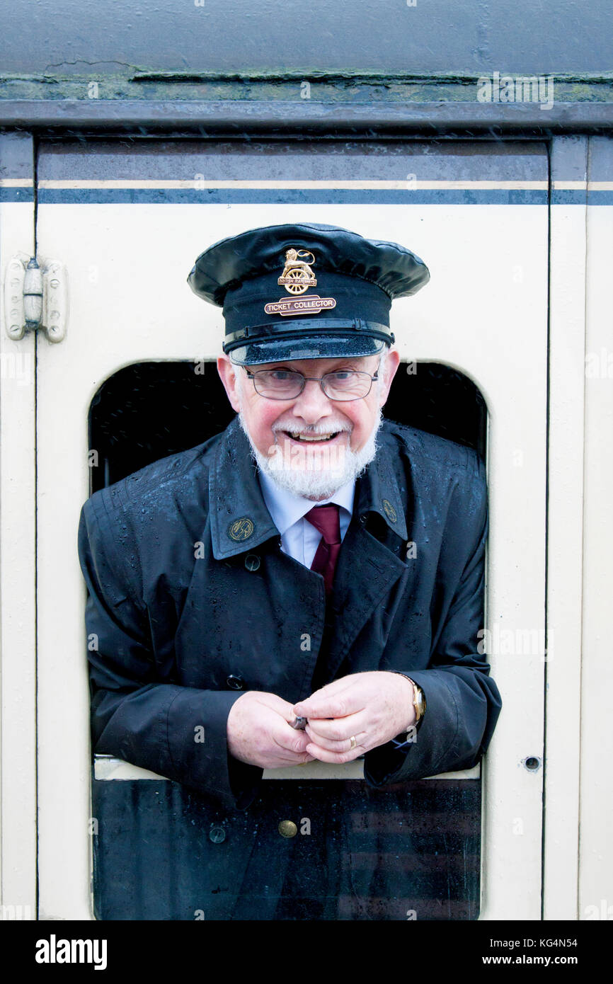 Ein Fahrkartensammler für die Dampfeisenbahn, der sich aus dem offenen Fenster einer alten Dampfeisenbahn lehnt, die in Somerset, Großbritannien, aufgenommen wurde Stockfoto