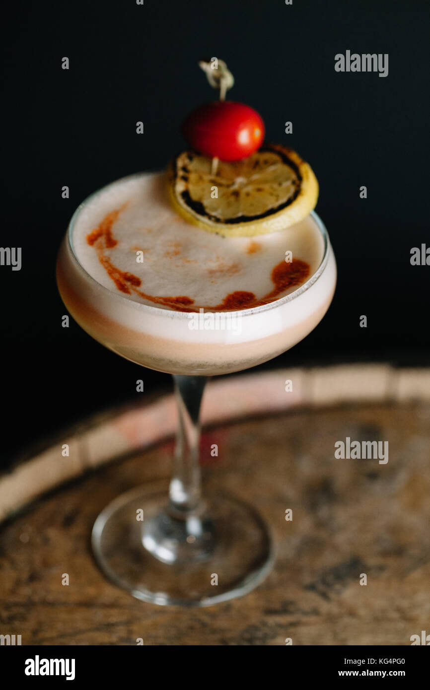 Einen alkoholfreien Cocktail mit Schaum, garniert mit Trauben Tomaten und eine Scheibe geräucherter Zitrone auf dunklem Hintergrund Stockfoto
