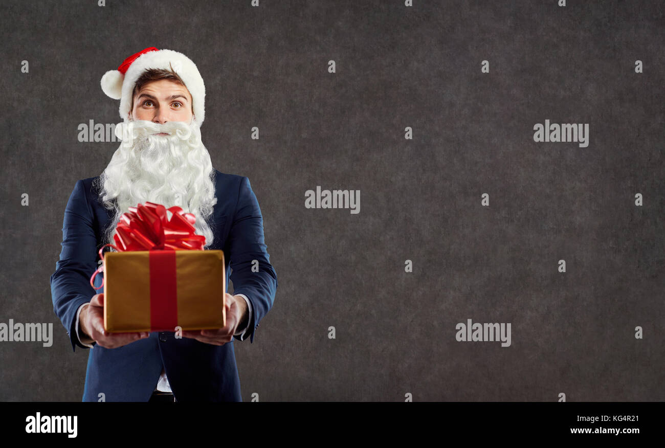 Geschäftsmann in santa claus Kostüm mit einem Geschenk in der Hand. Stockfoto