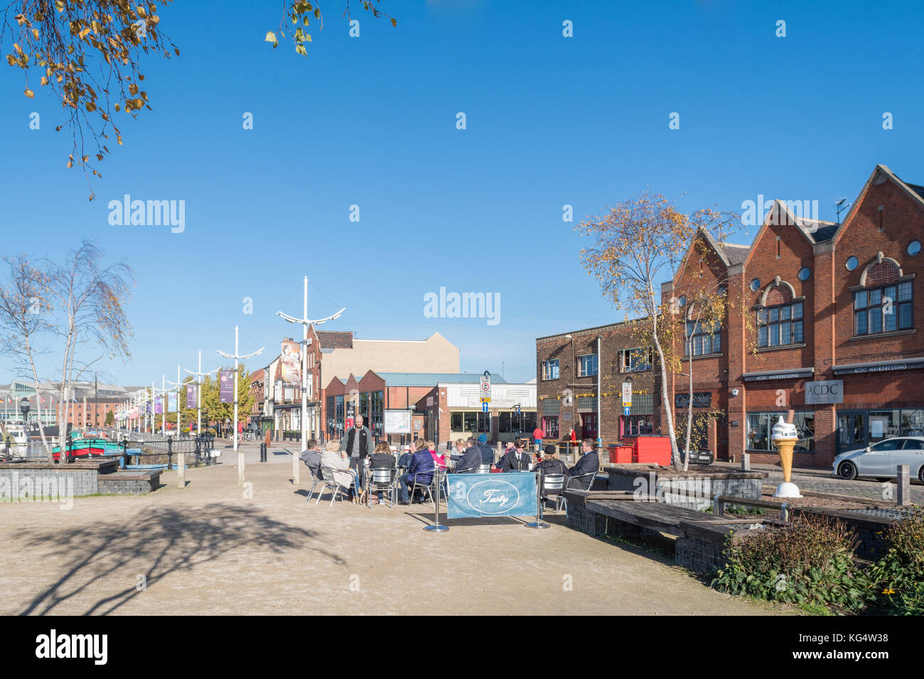Hull Marina - Menschen, die an einem hellen Herbsttag vor Restaurants und Cafés auf der Hull Marina Promenade sitzen, Kingston upon Hull, England, Großbritannien Stockfoto