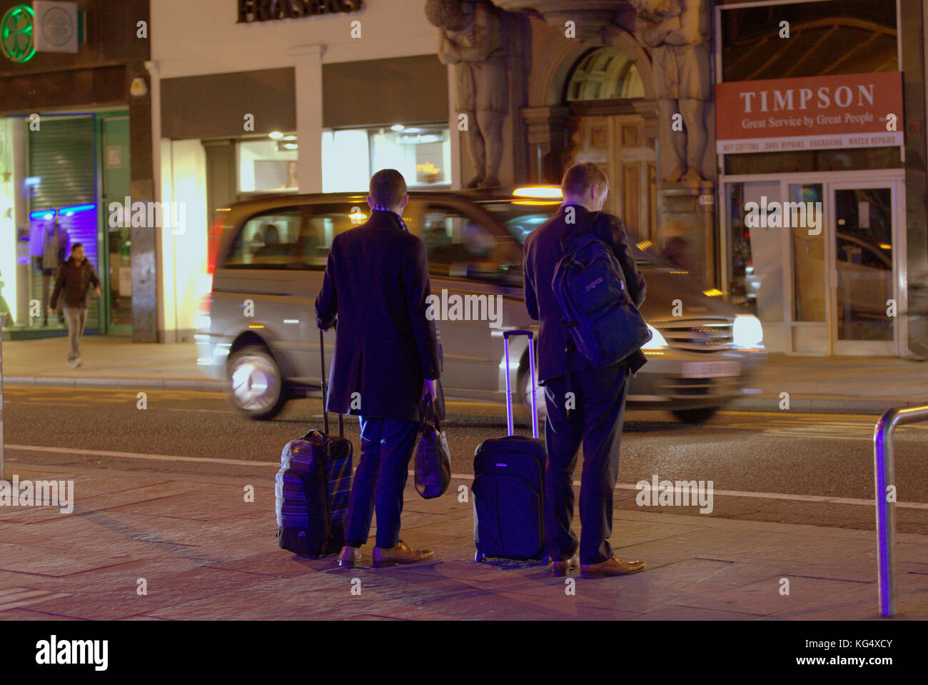 Touristen Geschäftsmann auf der belebten Straße mit Trolleys Taschen warten auf Taxi uber Fahrt auf dem Smartphone mobile gesehen von hinten Stockfoto