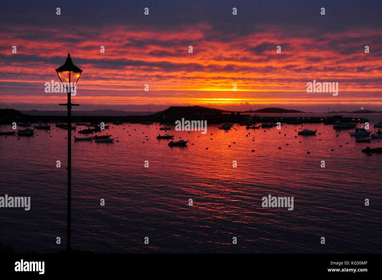 Sonnenuntergang über St Marys Hafen auf die Scilly-inseln, Lamp Post spiegelt die untergehende Sonne. Cornwall Großbritannien Stockfoto