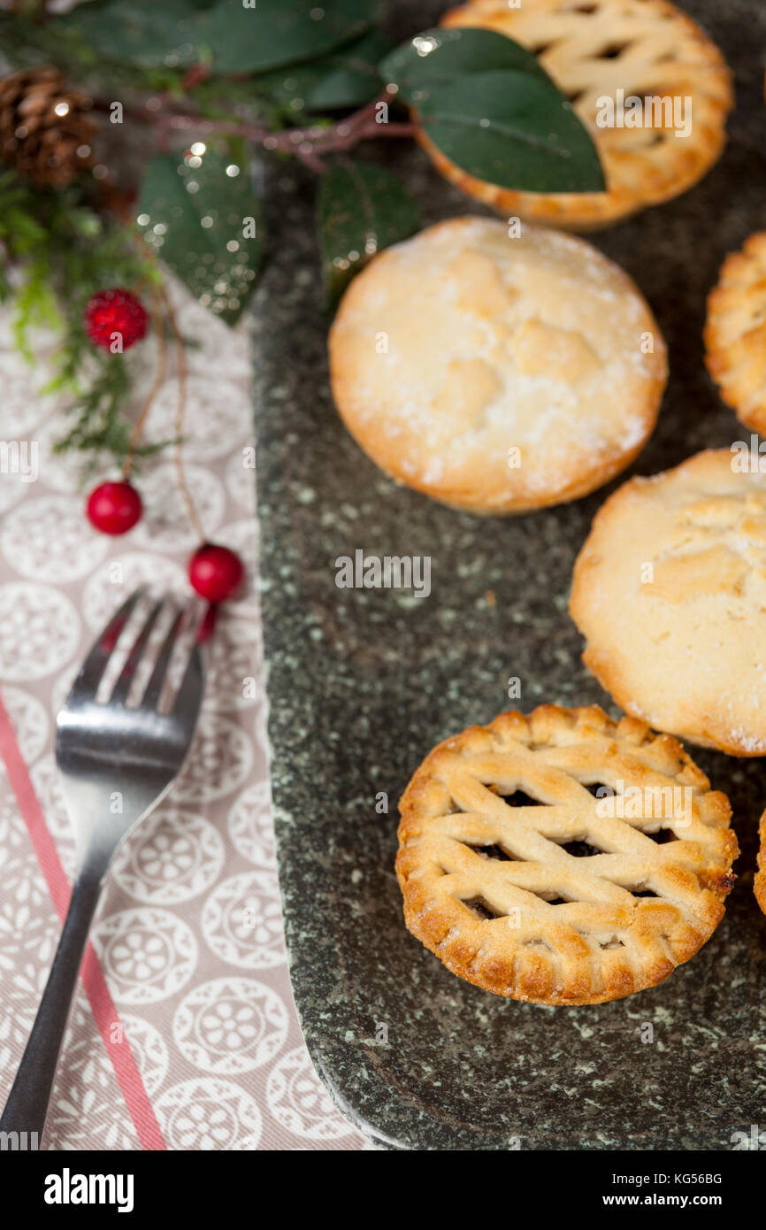 Auswahl an frischen frosted Mince Pies auf einem Tablett mit festlichen Weihnachtsschmuck auf ein Land Tabelle Stockfoto