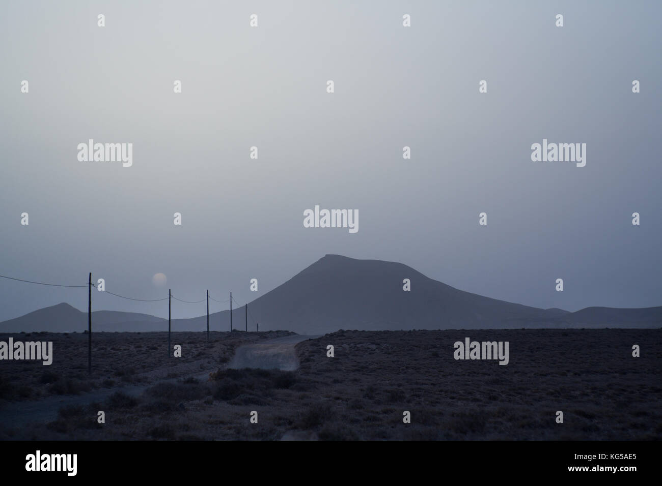 Fool moon Blick über eine leere Straße. wilde Landschaft mit Vulcan in Lanzarote Kanaren. kaltes Licht Stockfoto