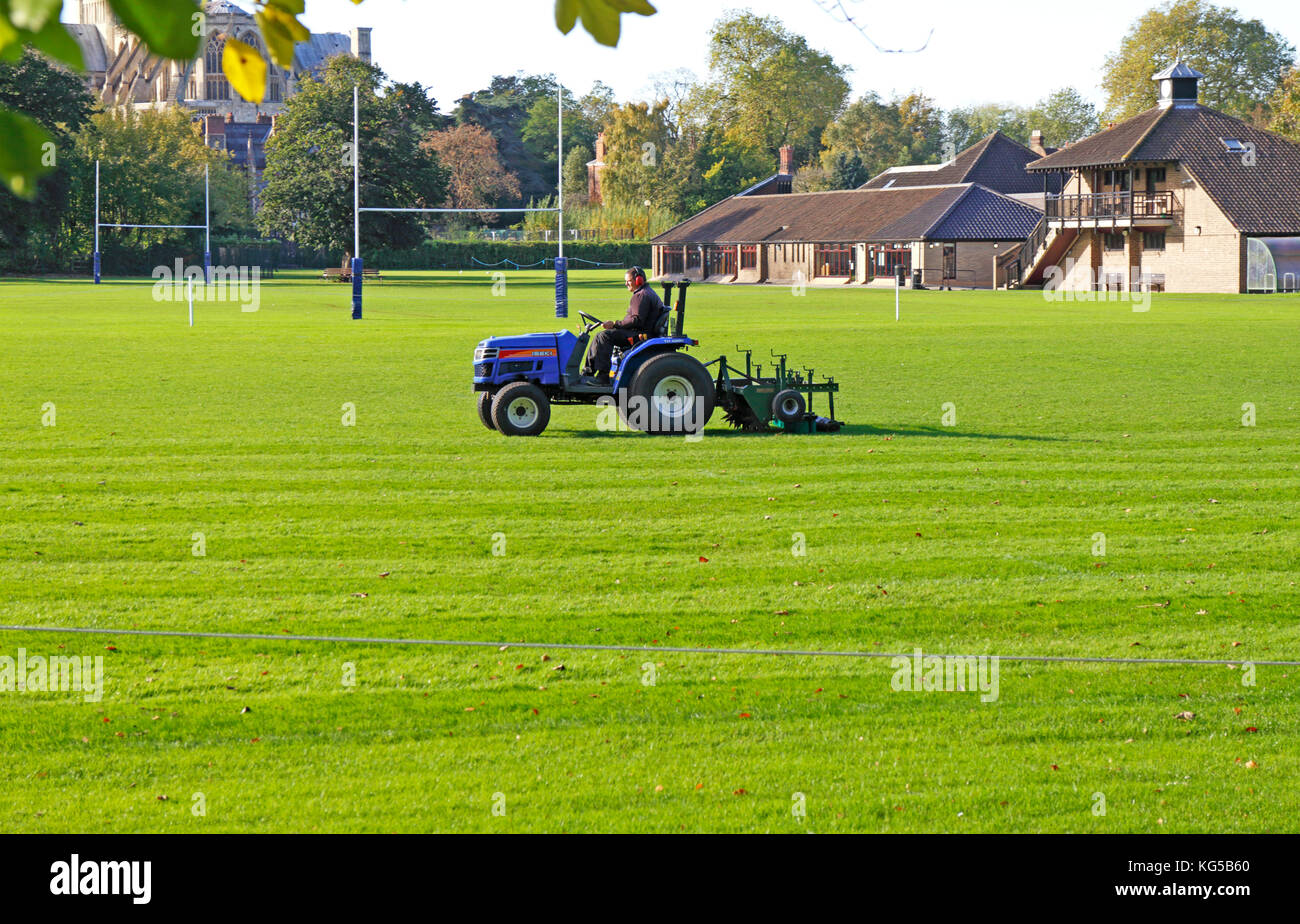 Gras schneiden mit Traktor und Cutter auf einer Schule Feld spielt. Stockfoto