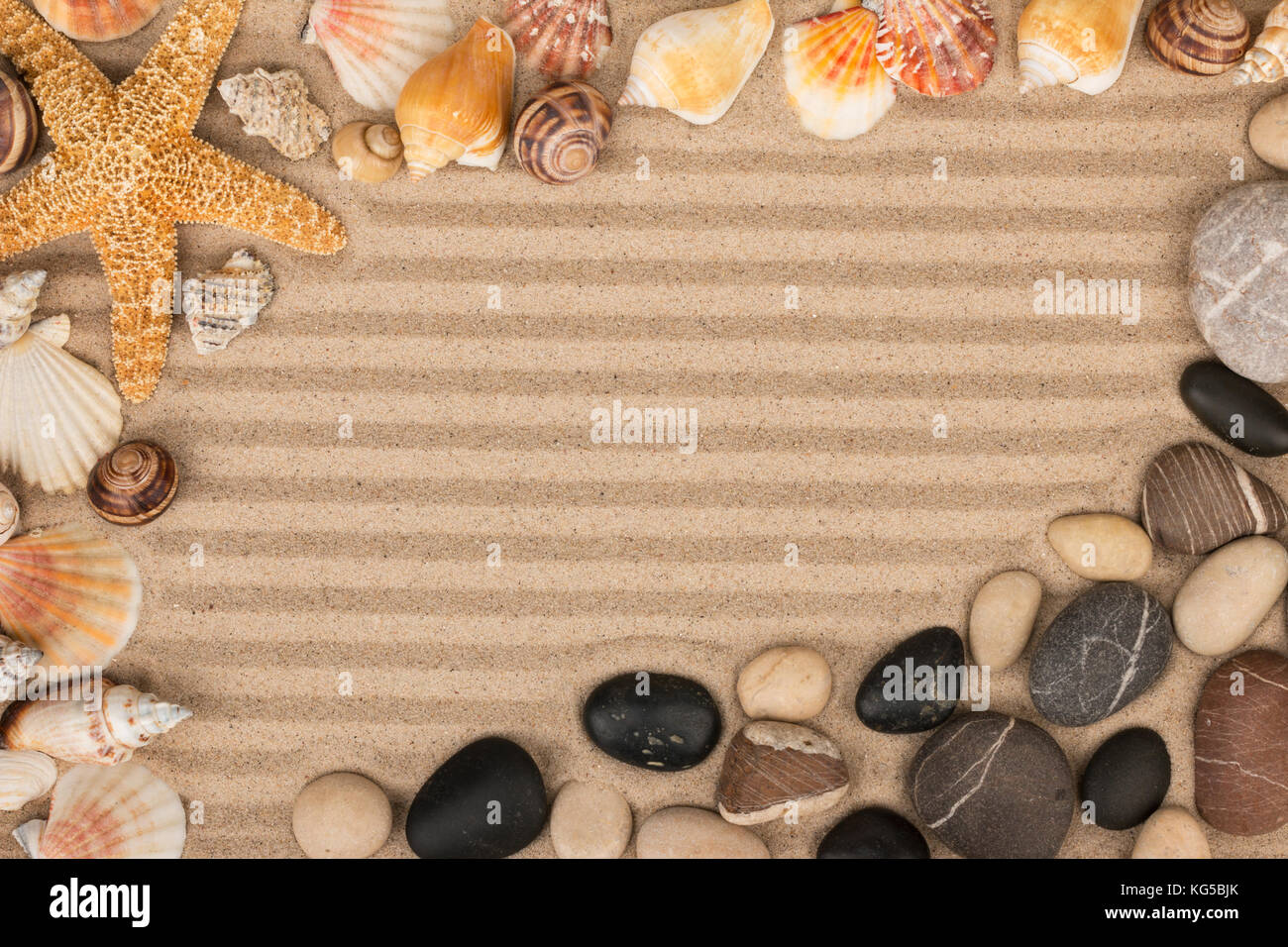 Rahmen aus Muscheln, Sterne und Steine liegen auf gestreifte Sand. Mit Raum für Ihre Kreativität Stockfoto
