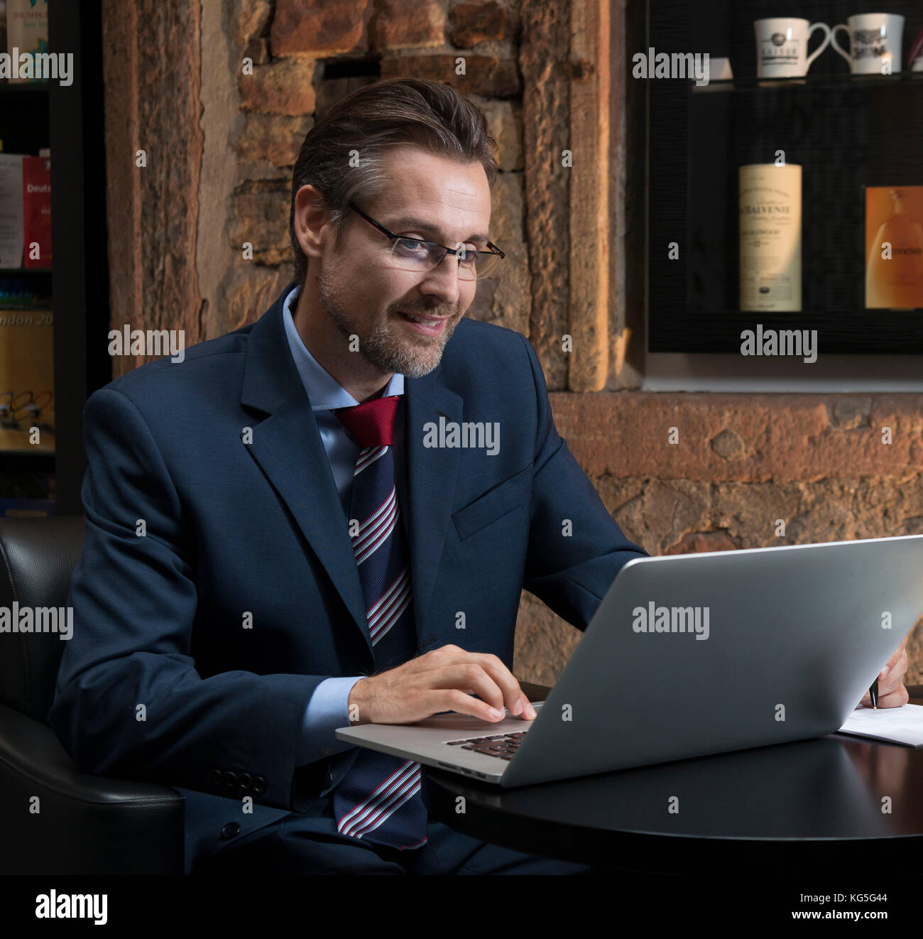 Mann in Anzug und Krawatte sitzt mit Laptop in der Lobby Stockfoto