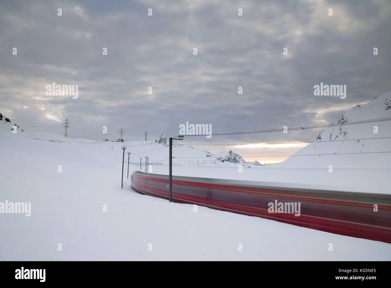 BERNINA Express fährt schnell in der verschneiten Landschaft bei Sonnenaufgang Bernina Pass Kanton Graubünden Engadin Schweiz Europa Stockfoto