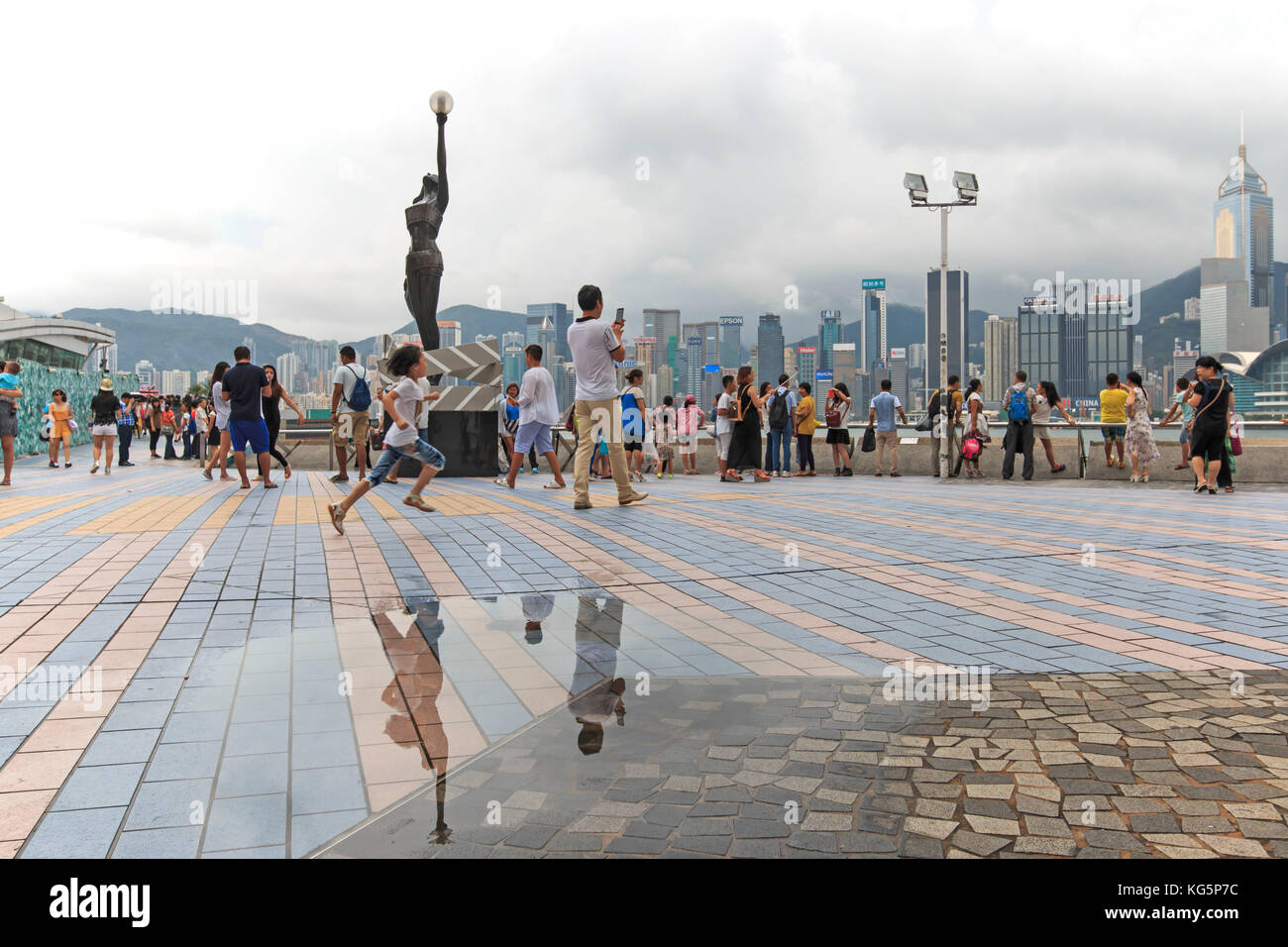 Touristen zu Fuß in der Nähe der Bronze Statue von Hong Kong Film Awards und Skyline in Avenue der Stars, China Stockfoto