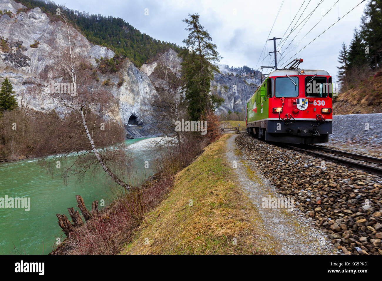 Der Rote Zug fährt am Rhein entlang. Rheinschlucht (Ruinaulta), Flims, Imboden, Graubünden, Schweiz, Europa Stockfoto