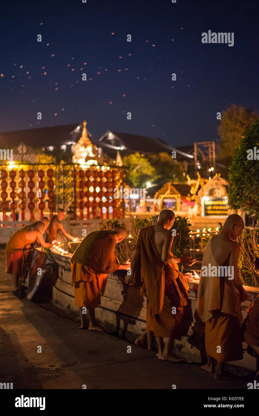 Mönche Beleuchtung Ton Kerze Schalen in der Nähe des Tempels Gebäude in Loy Krathong Festival mit vielen Feuer Laterne auf den Nachthimmel. Chiang Mai, Thailand. Stockfoto