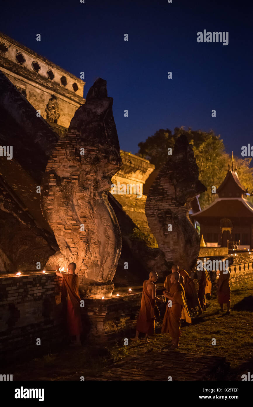 Mönch Beleuchtung der Ton Kerze Schalen in der Nähe der Naga Statue auf alten Pagode in Loy Krathong Festival im Chedi Luang Temple. Chiang Mai, Thailand. Stockfoto