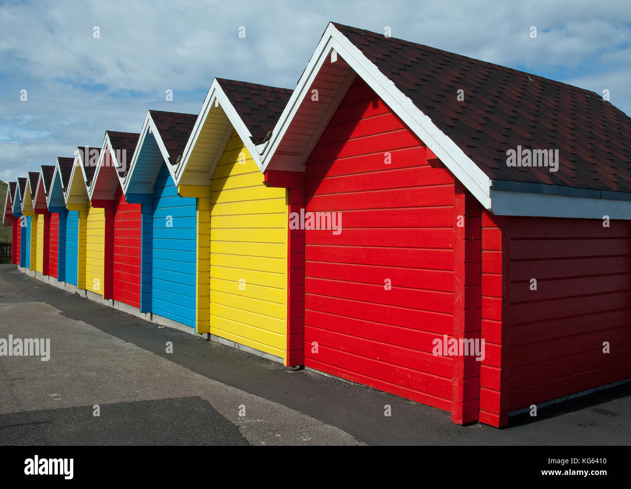 Ansicht der Rückseite einer Reihe von Giebel überdachter Britischen Strandhütten mit jeder Hütte individuell in rot, gelb oder blau lackiert Stockfoto