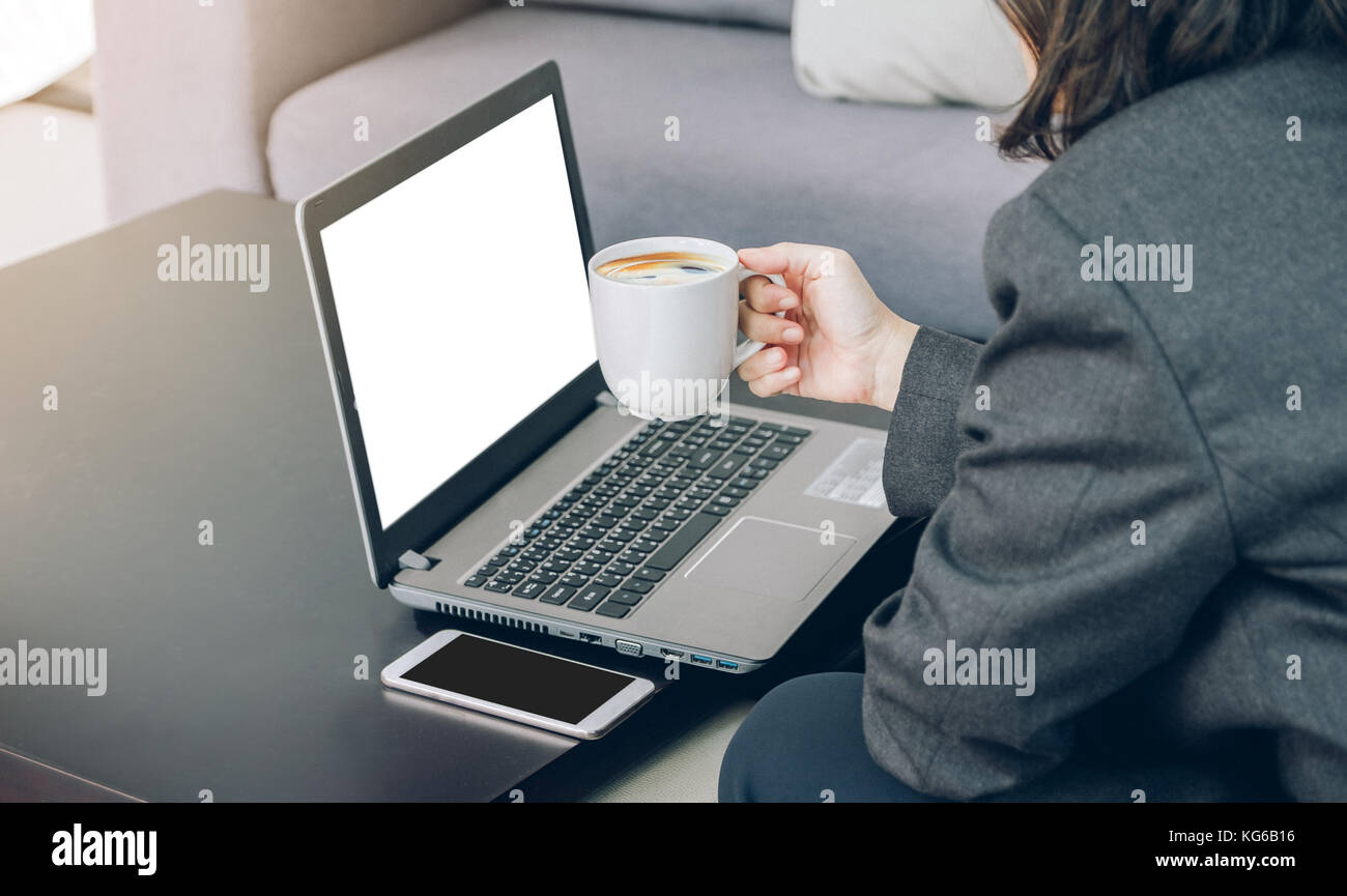 Geschäftsfrau holding Kaffee Tasse Arbeiten am Laptop und mobile Office, Mock up Leerer weißer Bildschirm Computer für die Anzeige von Design Content, digital Mark Stockfoto