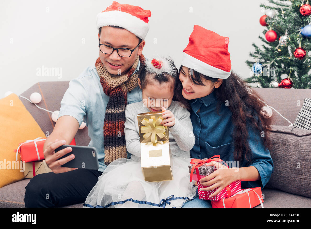 Glückliche Familie Asien selfie mit mobilen am Sofa, Vater und Mutter tragen der Weihnachtsmann hat zu Weihnachten schenken Geschenk Box zu Kind im Haus Xmas Party, Urlaub celeb Stockfoto