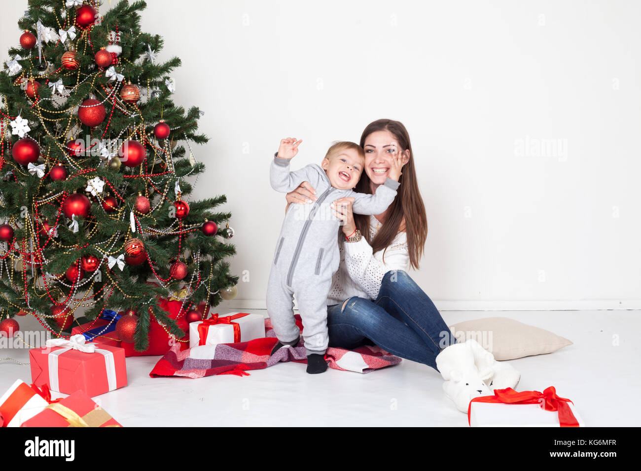 Mutter und kleinen Jungen am Weihnachtsbaum mit Geschenken 1. Stockfoto