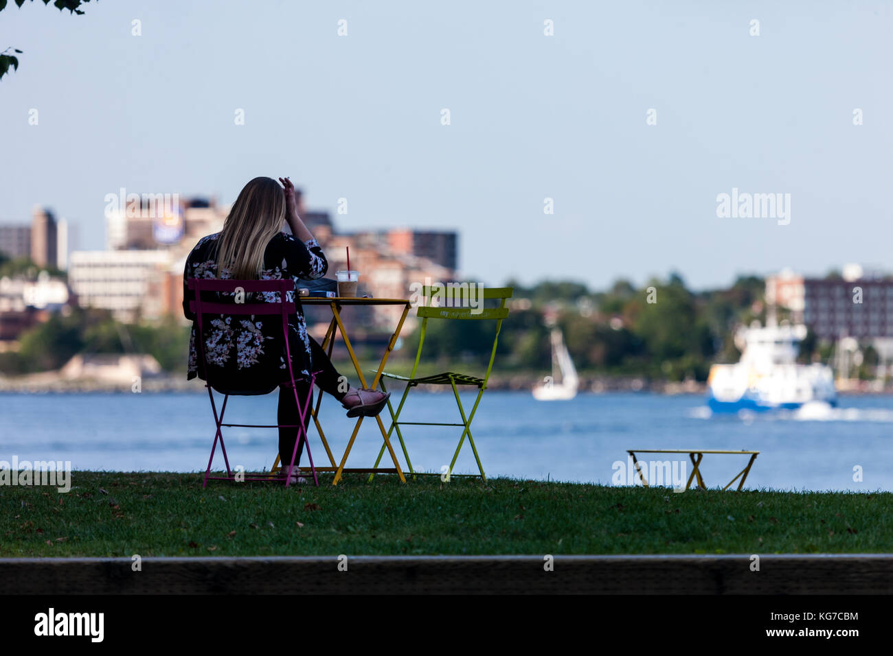 Halifax, Kanada - 29 August 2017: eine Frau sitzt auf einem Hügel mit Blick auf den Hafen von Halifax. Stockfoto