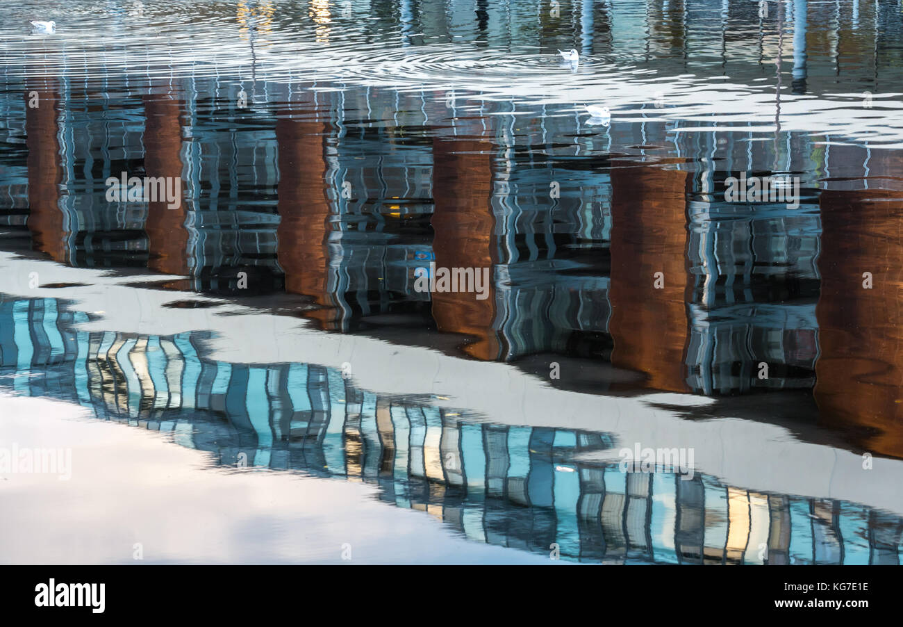 Reflexionen der modernen Mehrfamilienhaus in ruhigem Wasser Wasser von Leith Fluss, Erstellen von Welligen abstrakte Muster, Edinburgh, Schottland, Großbritannien Stockfoto