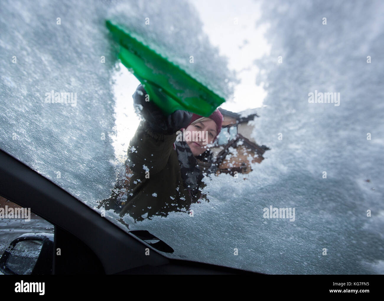 Frau schabt Eis vom Autofenster Stockfoto