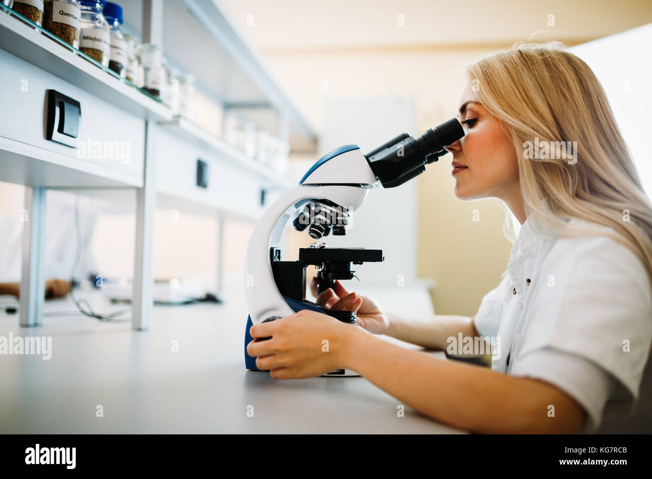 Junge Wissenschaftler durch Mikroskop im Labor auf der Suche Stockfoto
