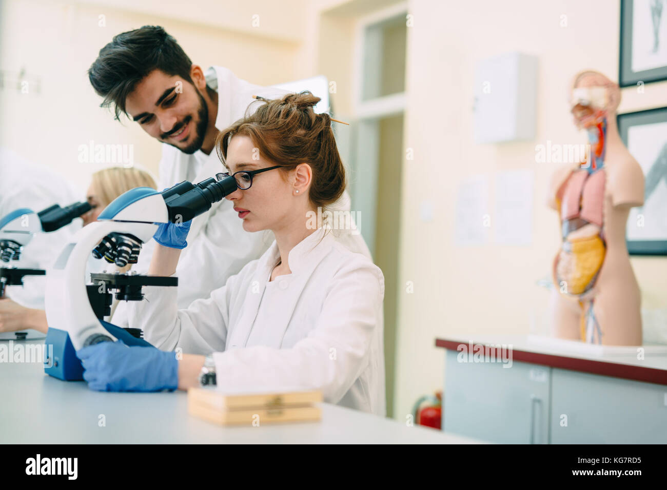 Junge Wissenschaftler durch Mikroskop im Labor auf der Suche Stockfoto