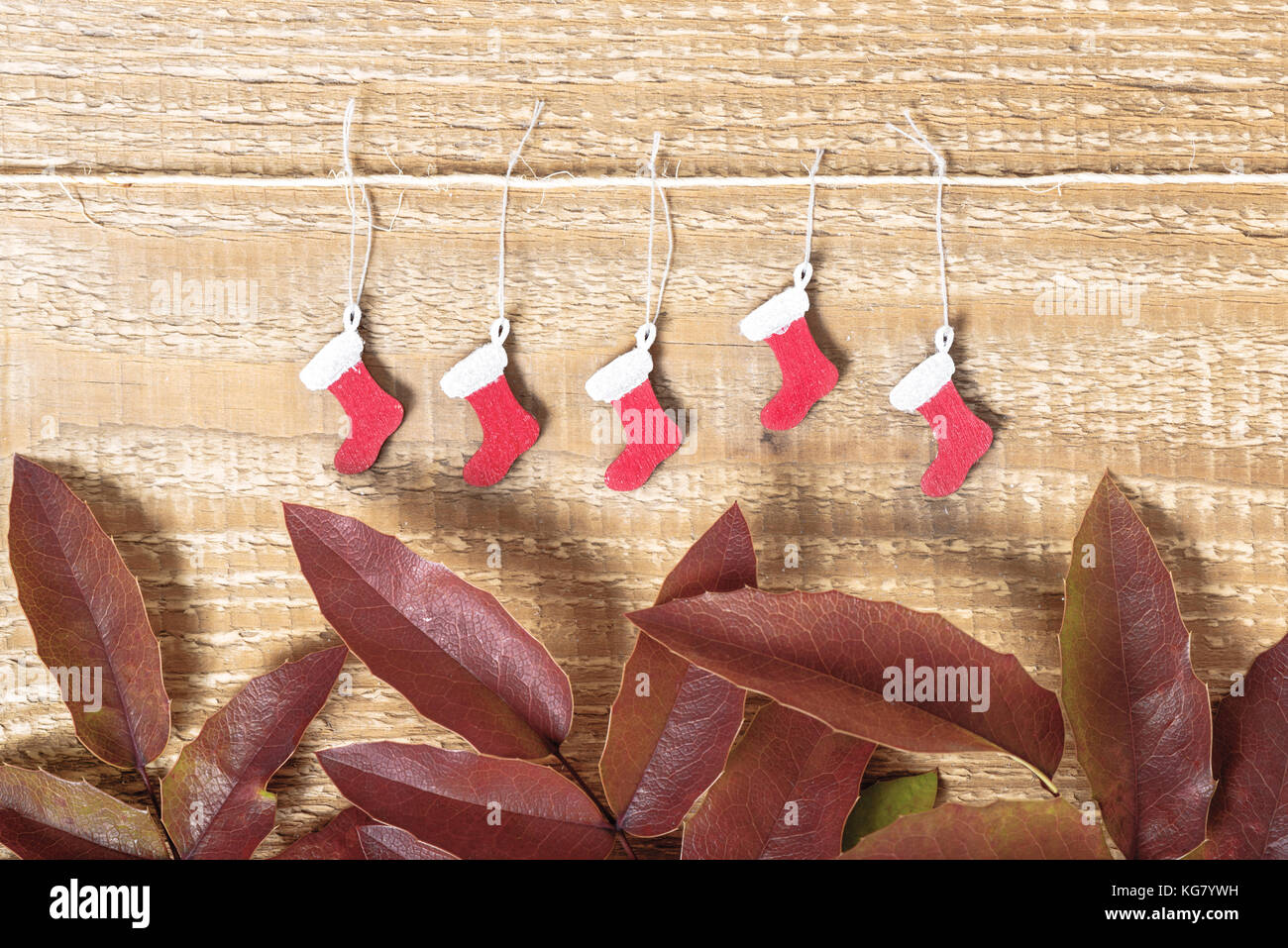 Weihnachten Hintergrund dekoriert mit bemalten santa Stiefel auf Holz- oberfläche und rote Blätter, Nahaufnahme Stockfoto