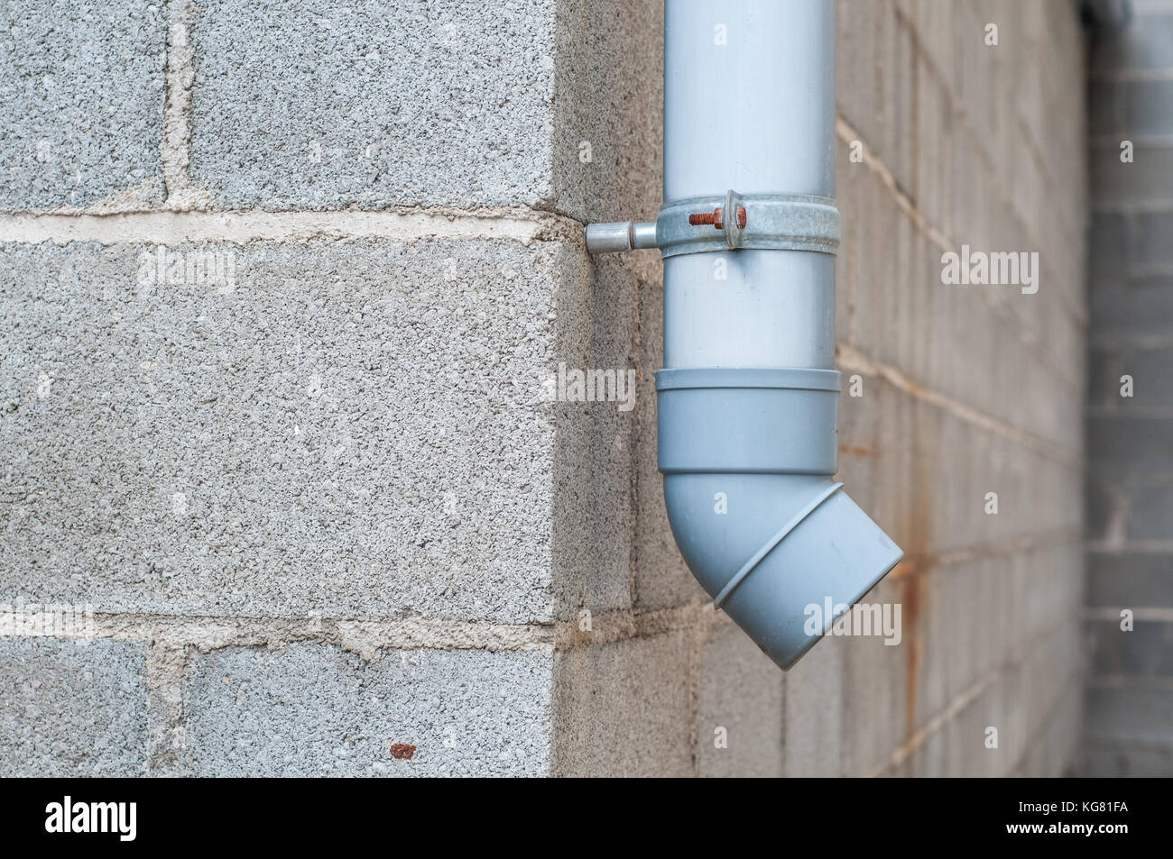 Industrielle Wasser ablassen PVC-Rohr mit Betonklotz im Hintergrund Stockfoto