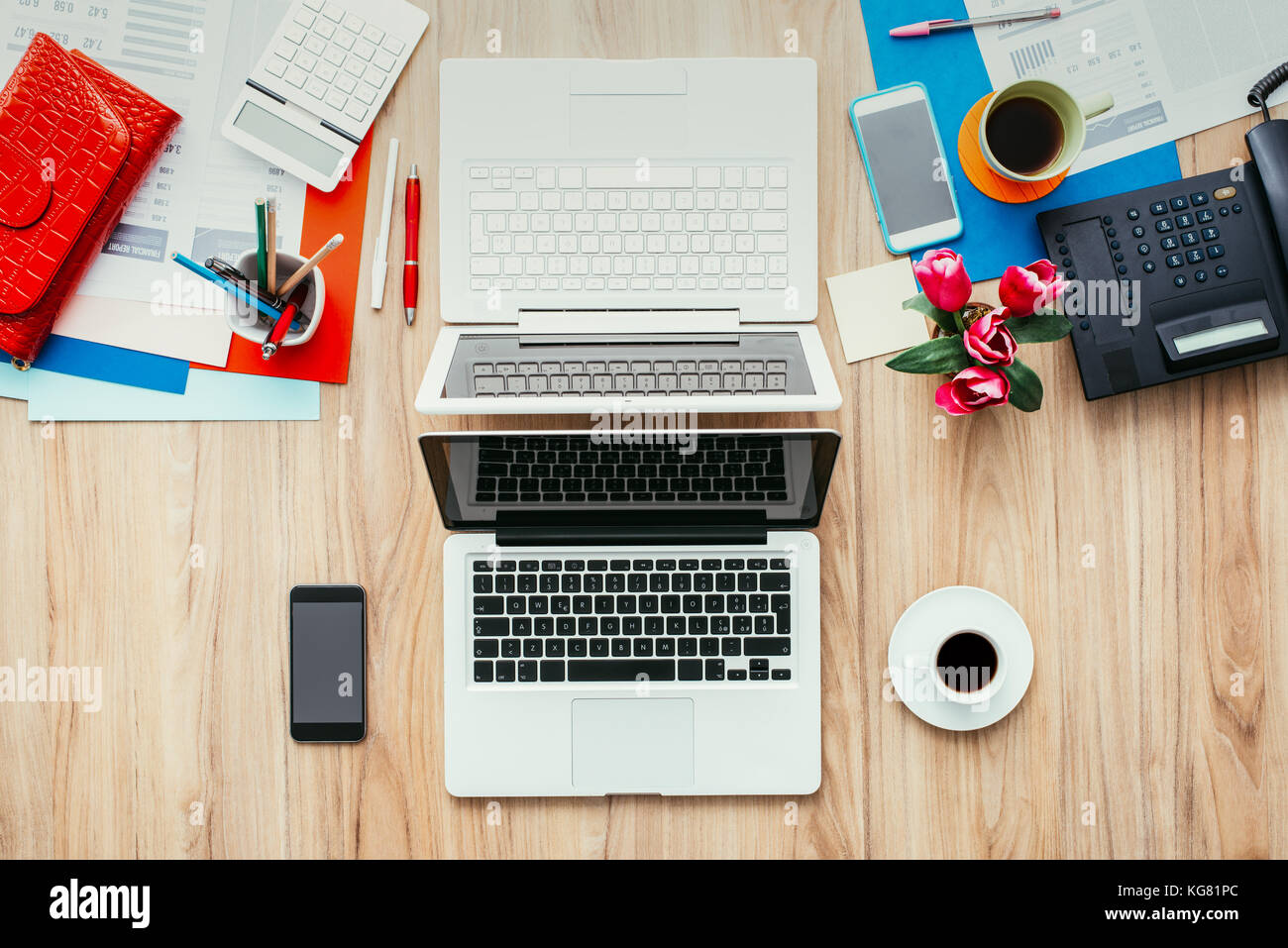 Feminine kreative unordentlichen Desktop vor einem männlichen einfachen und effizienten Arbeitsbereich mit Laptops in der Mitte, Coworking und Business Konzept Stockfoto