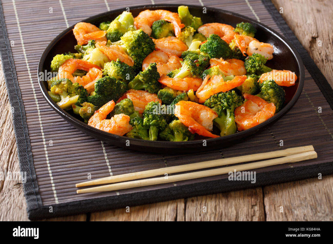 Pfannengerichte mit Garnelen, Brokkoli und Knoblauch - chinesisches Essen. Closeup auf einem Teller. Horizontale Stockfoto