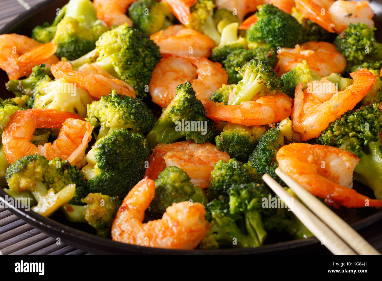 Braten Garnelen mit Brokkoli und Knoblauch Makro auf einem Teller einrühren. Horizontale Stockfoto