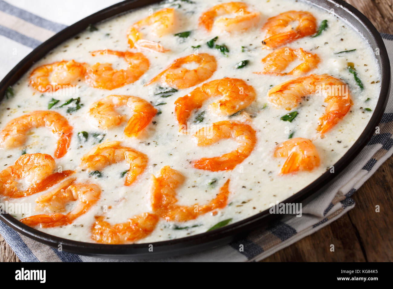 Riesengarnelen mit Spinat und Knoblauch in cremige Käse sauce Close-up auf einem Teller auf dem Tisch. Horizontale Stockfoto