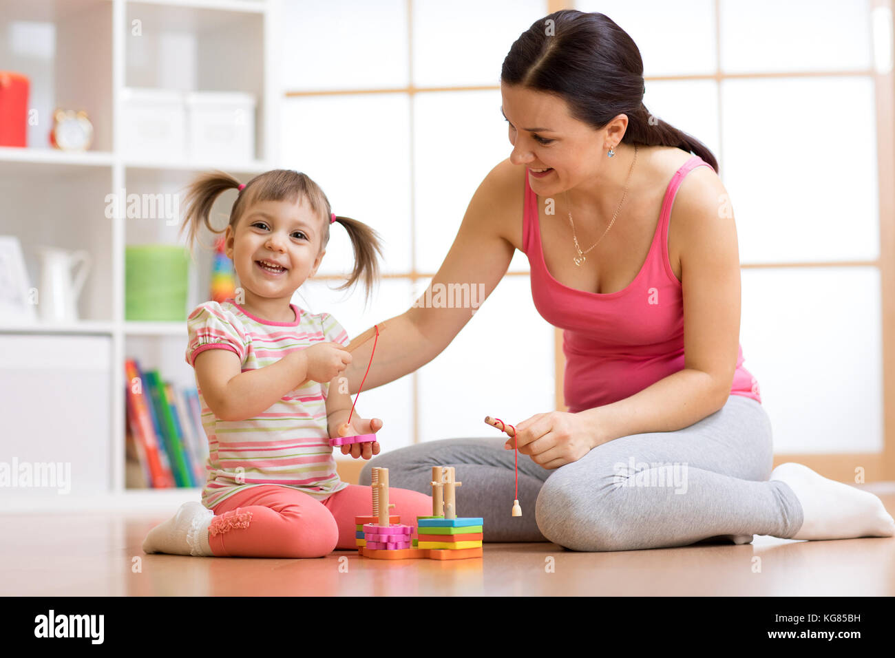 Süße Frau und Kind Mädchen spielen pädagogische Spielwaren zu Hause Stockfoto