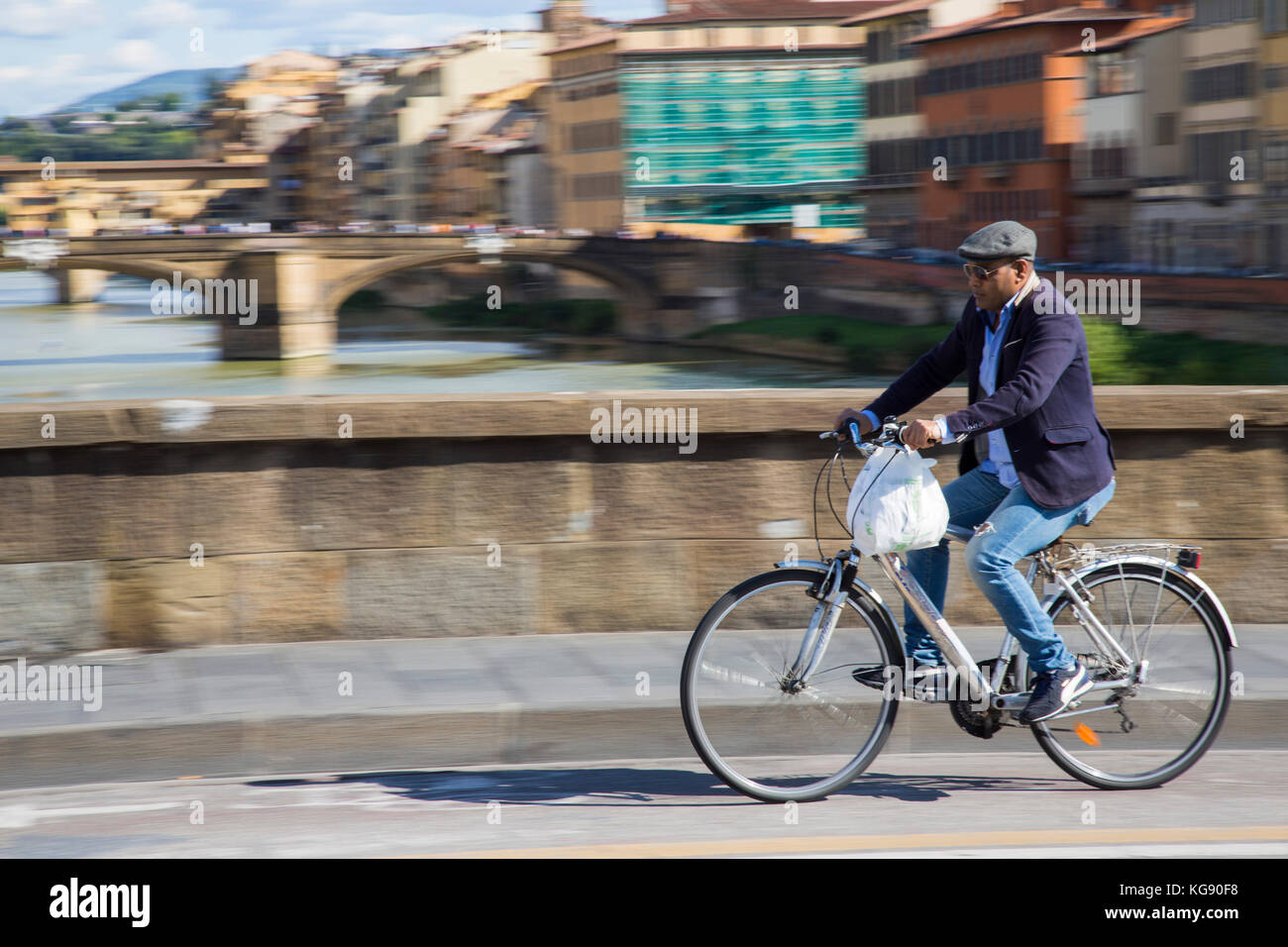 Gentleman Radfahrer reiten über eine Brücke in Florenz vor dem Hintergrund der Ponte Vecchio. Stockfoto