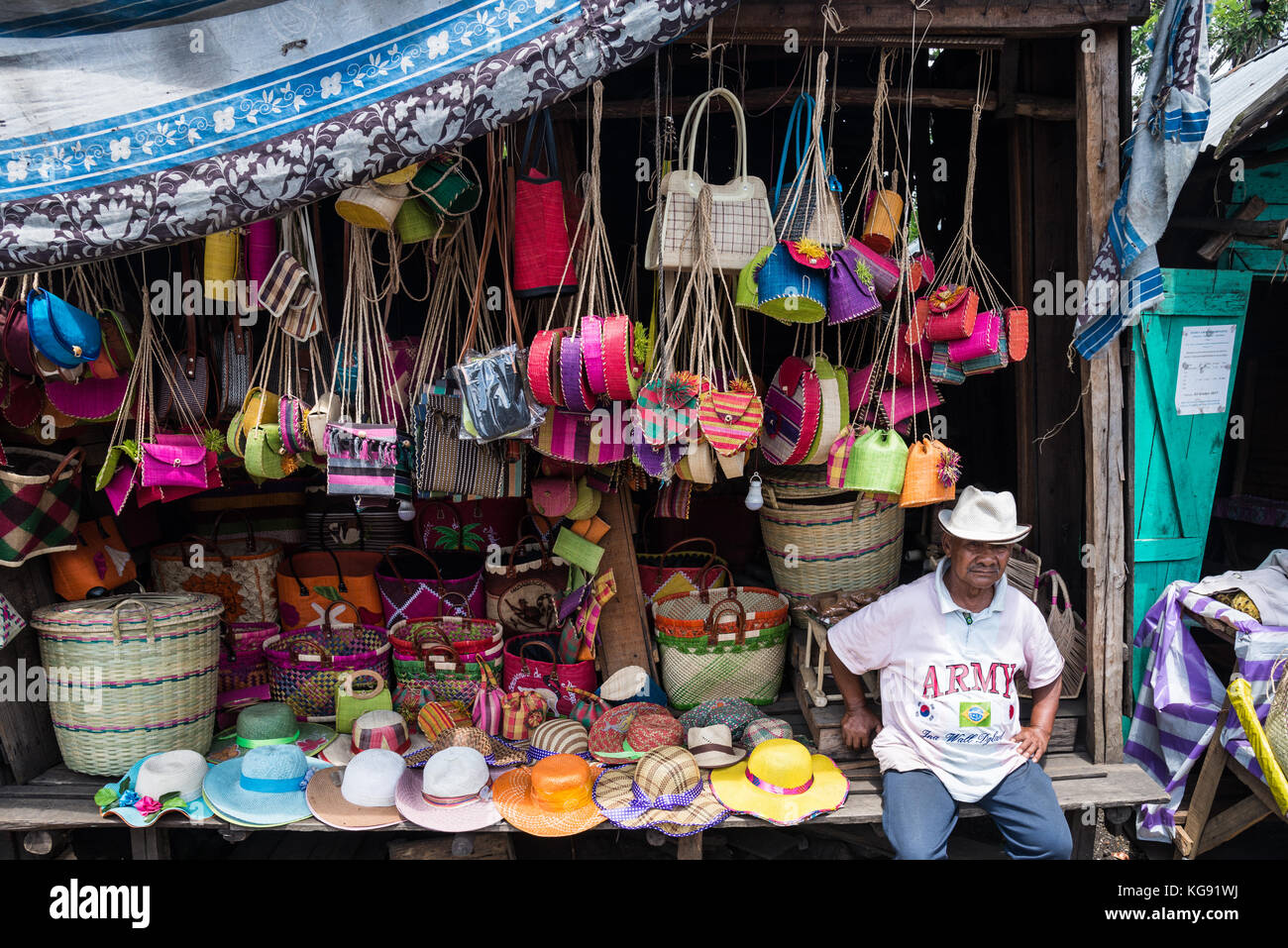 Ein madagassischer Mann sitzen vor seinem Stall mit Souvenirs und regionale Produkte in einem Markt. in Madagaskar, Afrika. Stockfoto