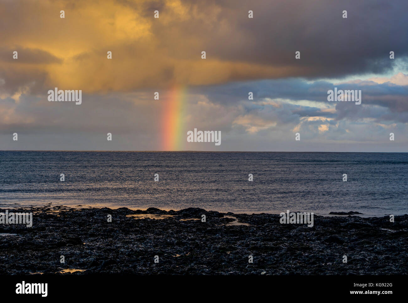 Regenbogen über dem Atlantischen Ozean bei Sonnenuntergang in Island Stockfoto