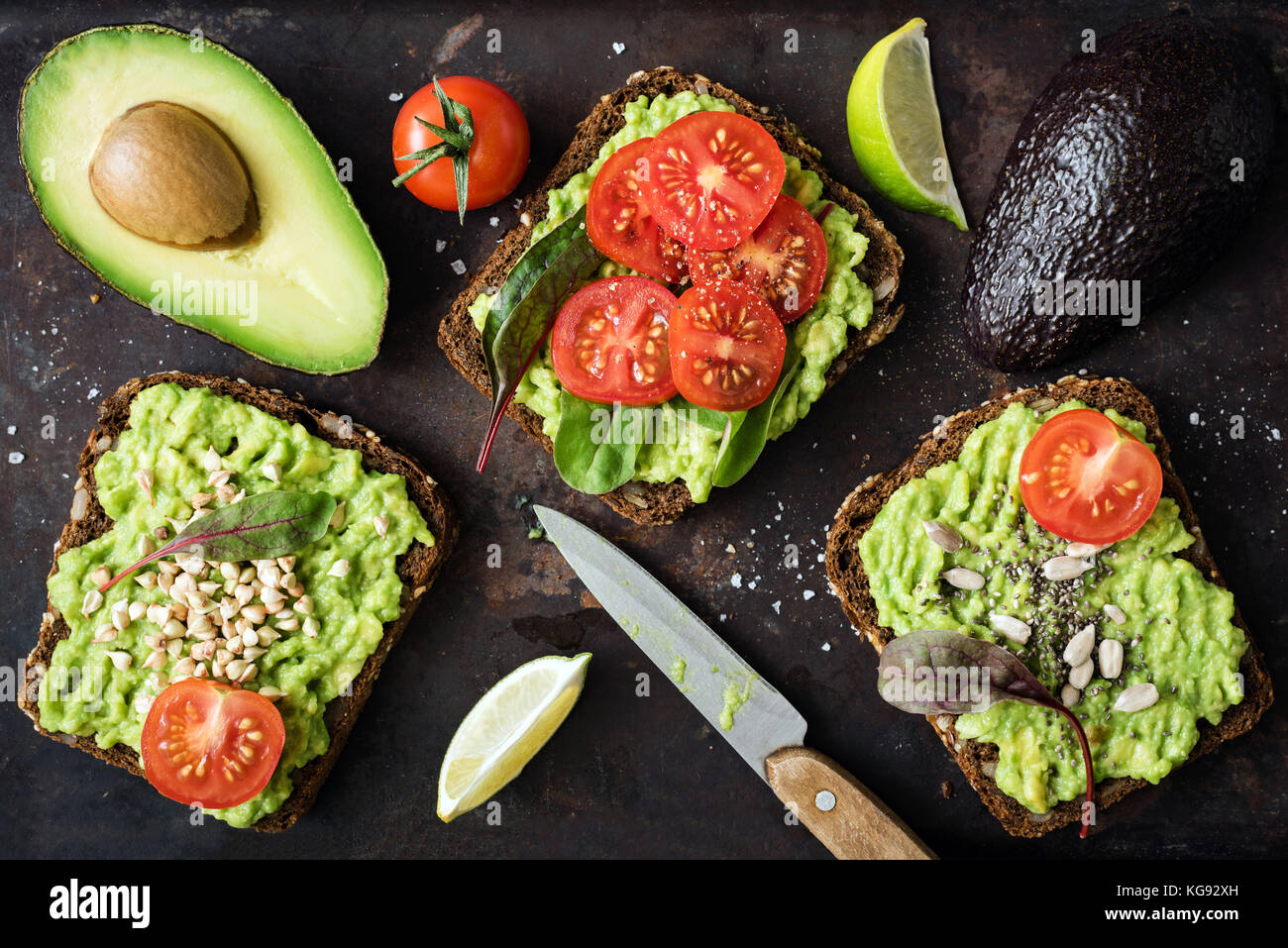 Gesunden grünen veggie Toast mit Avocado, Tomaten, Sprossen und Samen auf dunklen backgrop. table top anzeigen. gesunde Lebensmittel, vegane Ernährung Konzept Stockfoto