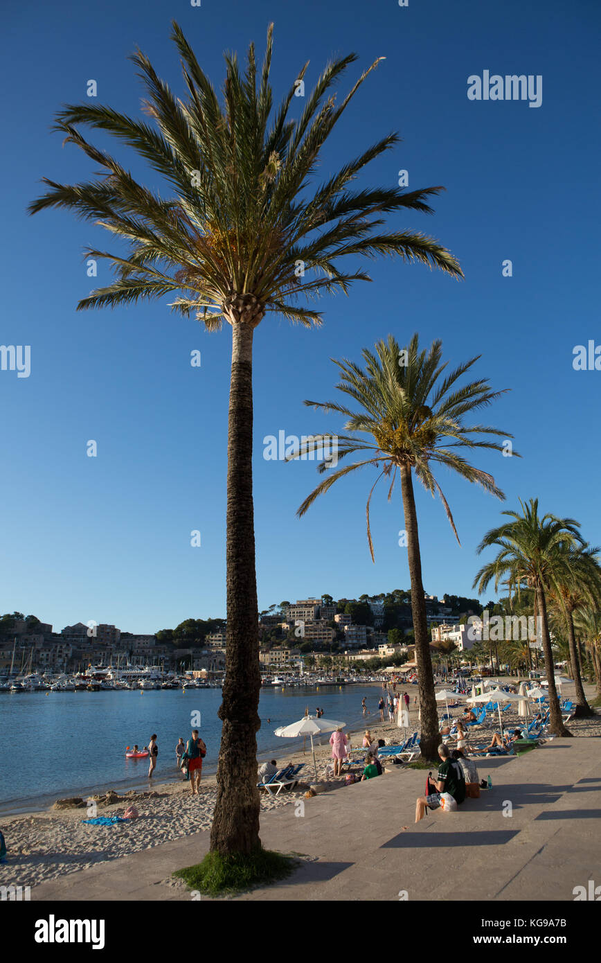 Touristen entspannen und genießen am Strand, Stadt und Hafen im Hintergrund, Port de Soller, Mallorca, Balearen, Spanien. Stockfoto
