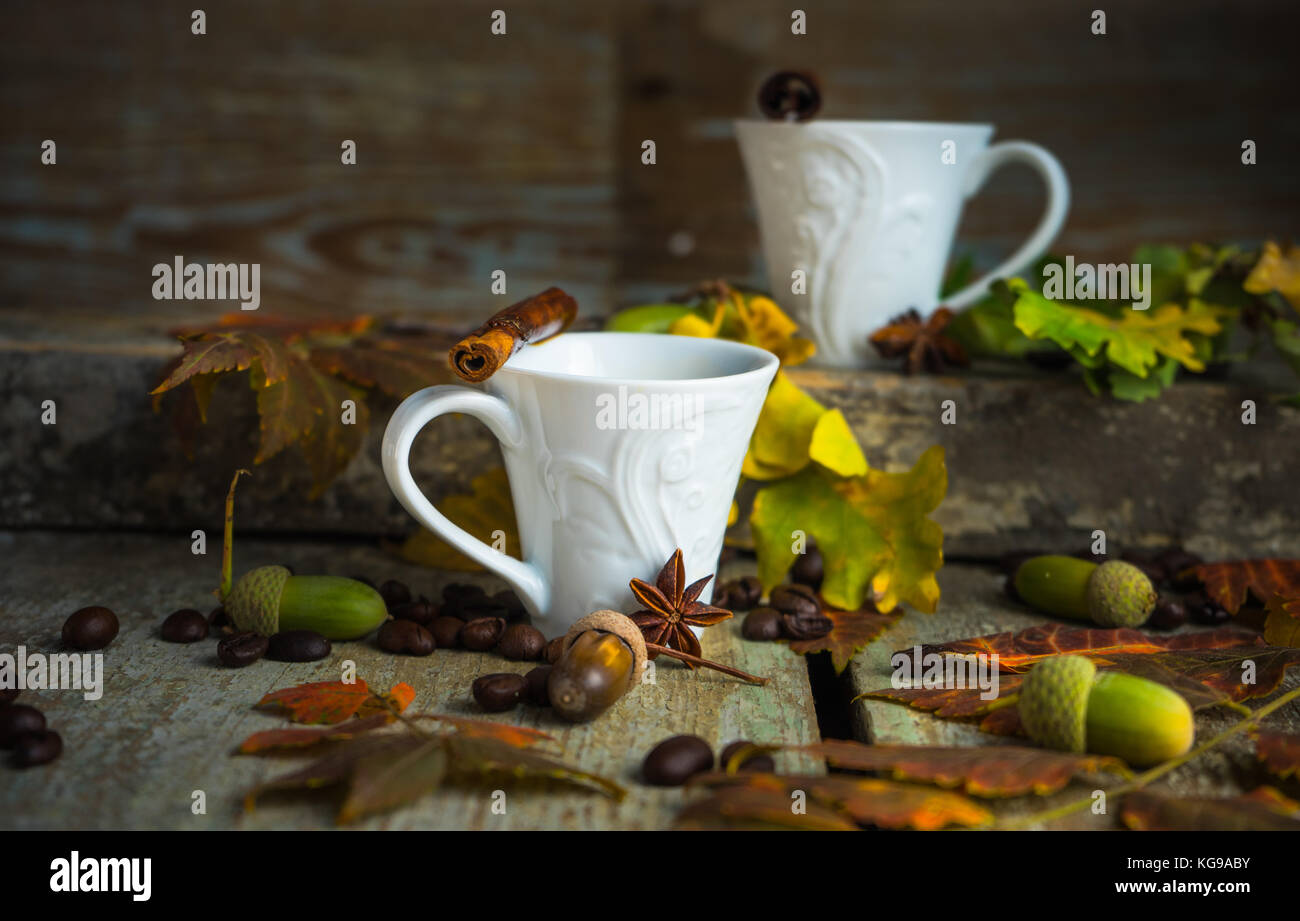 Herbstliche Konzept mit mup Kaffee mit Gewürzen, Zimtstange und Anis Sterne auf rustikalen Holzmöbeln Hintergrund voller Eiche hell gelbe Blätter und Eicheln Stockfoto