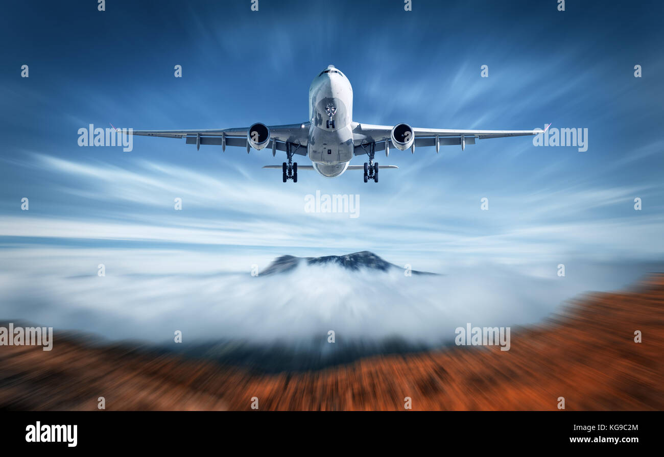 Flugzeuge mith motion blur Effekt ist Fliegen über niedrige Wolken. Landschaft mit Passagierflugzeug, unscharfe Wolken, Berge, blauer Himmel. Passagierflugzeug Stockfoto