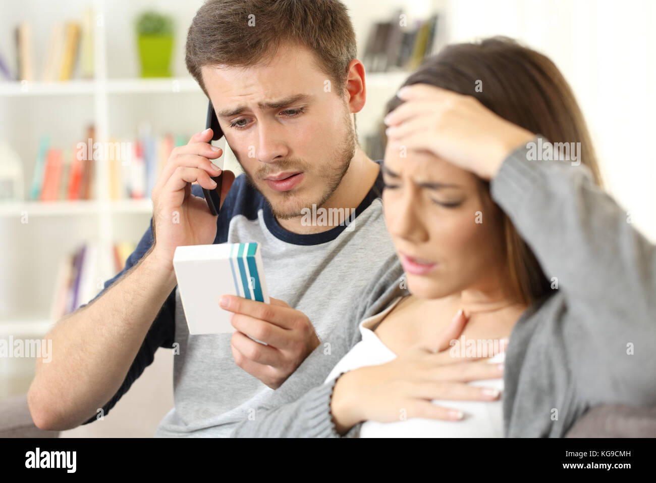 Mann anrufen Arzt fragen, Frau Medizin Allergien oder Nebenwirkungen sitzen auf einem Sofa in einem Haus innen Stockfoto