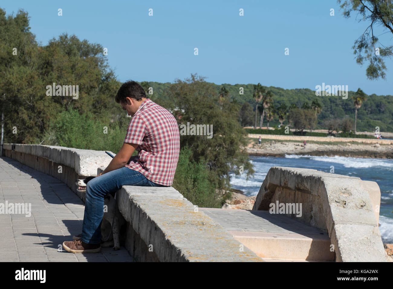 Junger Mann auf Handy, durch das Meer, Mallorca, Spanien Stockfoto