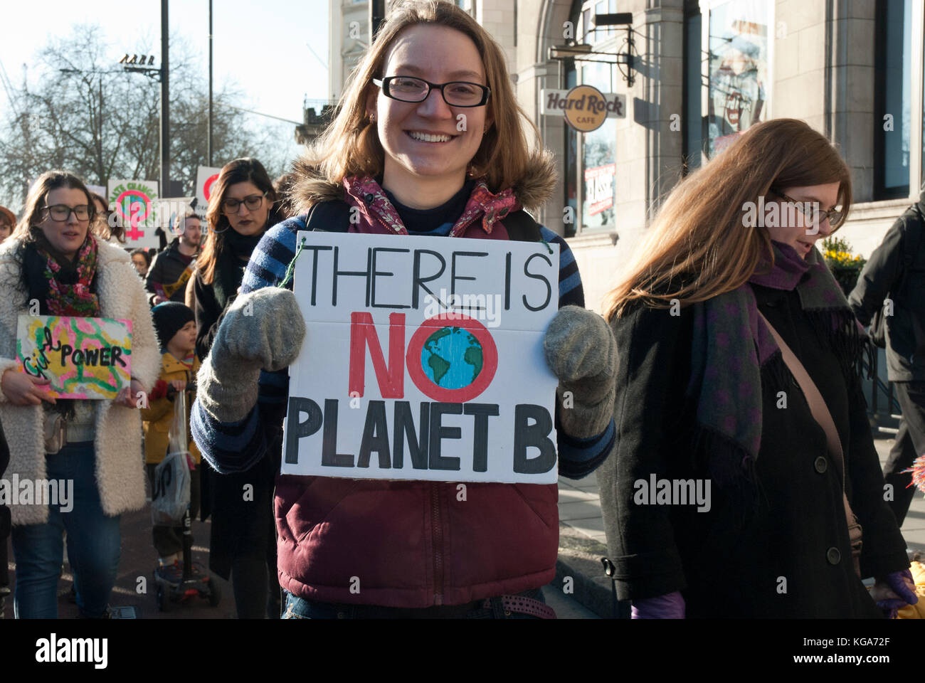 Eine junge lächelnde Aktivist Holding ein Plakat "Es gibt keine Pflanze b" mit einem Bild des Planeten Erde, als Kommentar auf die globale Erwärmung/Umwelt Stockfoto