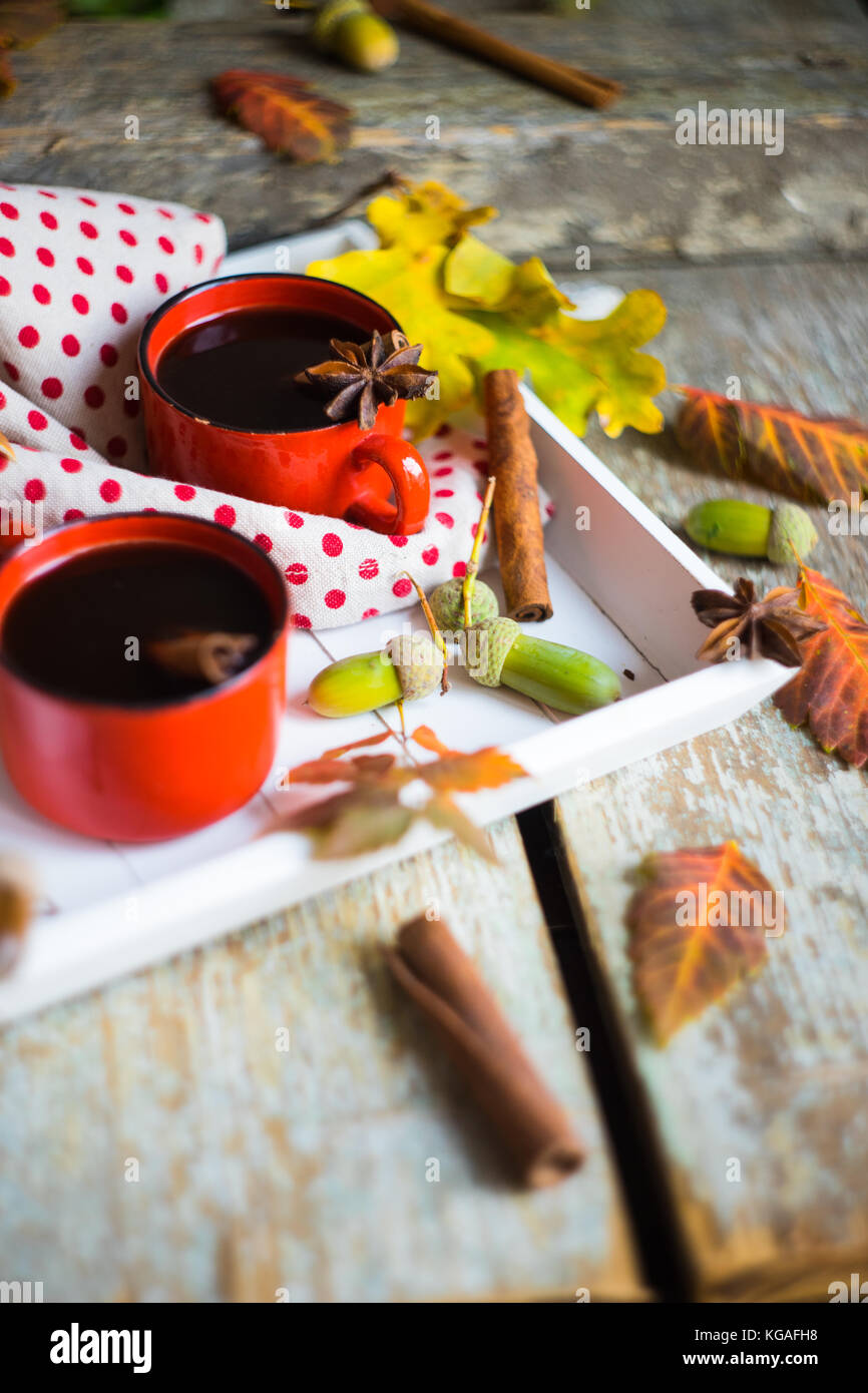 Herbstliche Konzept mit mup Kaffee mit Gewürzen, Zimtstange und Anis Sterne auf rustikalen Holzmöbeln Hintergrund voller Eiche hell gelbe Blätter und Eicheln Stockfoto