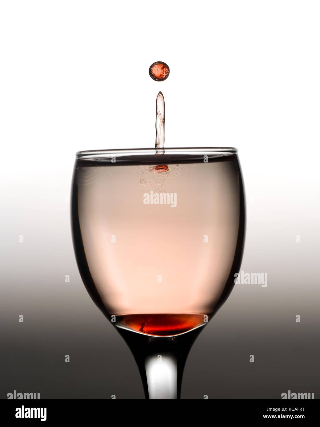 Farbige Wassertropfen spritzen in Kristall Glas Wein Stockfoto