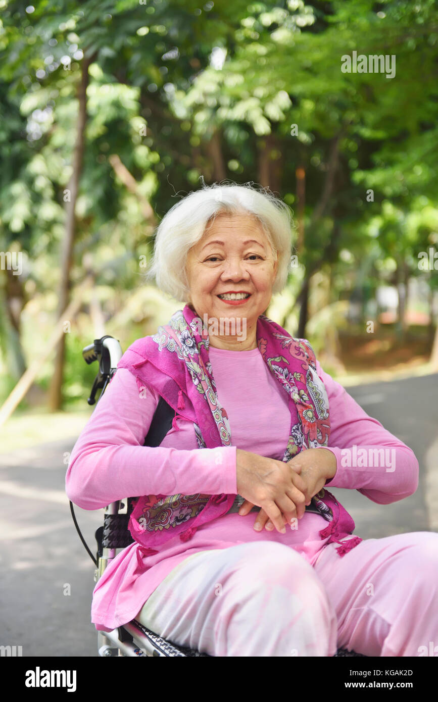 Portrait von asiatischen Senior Frau sitzt auf einem Rollstuhl im Freien Stockfoto