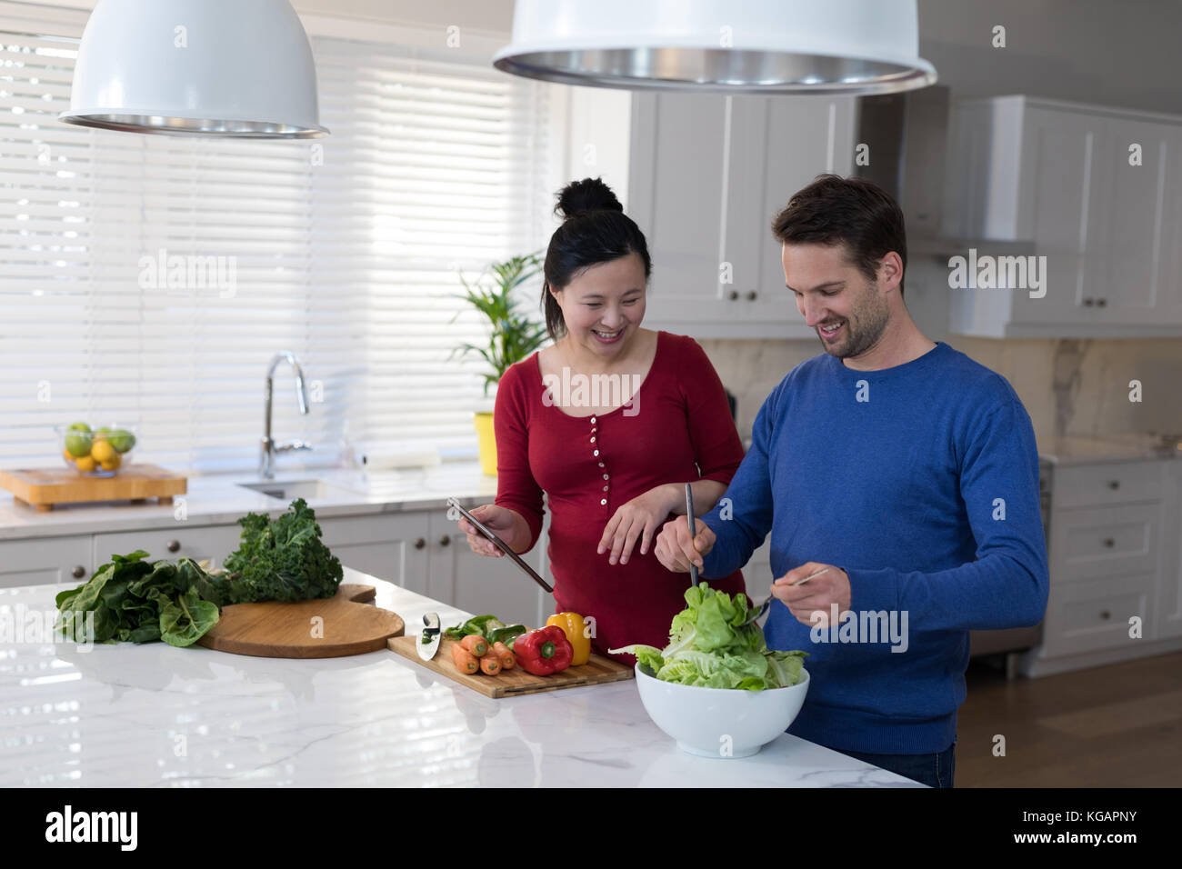 Lächelnd schwangeren Paare Vorbereitung Salat in der Küche Stockfoto