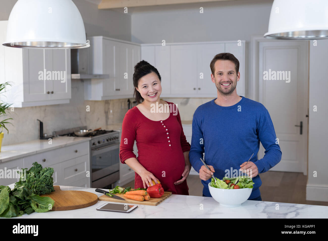 Lächelnd schwangeren Paare Vorbereitung Salat in der Küche Stockfoto