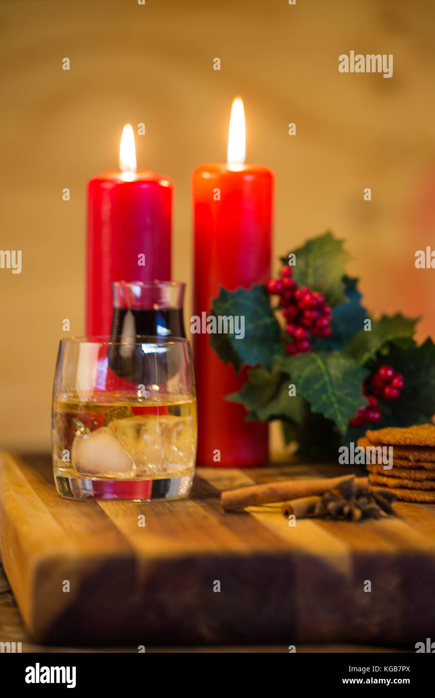 Schöne Nahaufnahme Bild von Weihnachtsplätzchen auf einer hölzernen Schneidebrett mit einigen Duftkerzen und einem Glas Whiskey/Kaffee und etwas Zimtstange Stockfoto